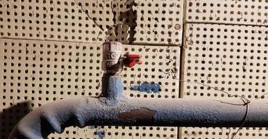 Antigua pipa de agua azul y grifo rojo en una casa abandonada en una pared rota foto