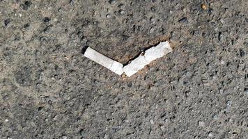 Close up of a broken cigarette butt on asphalt with copy space. International No Tobacco Day. World Day against cigarettes, nicotine and tobacco photo