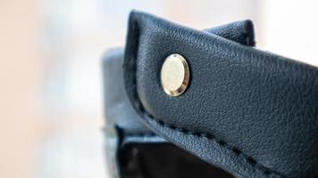 Detail of a fashionable black leather handbag close-up. Fashion concept. Details of a belt, metal buckle, fastener, sewing threads, macro photography. Stylish female accessory. photo