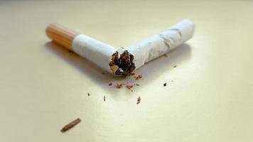 Broken cigarette isolated on a yellow background. View from above photo