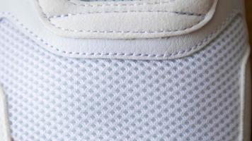 White color mesh fabric on a part of sports shoes. Running shoe net. Sportswear textured lattice. Textile texture background. Detail of a white sneaker in fabric with laces. Fragment of sports shoes. photo