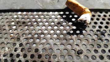 Una colilla de cigarrillo en un cenicero público con un fondo de metal foto