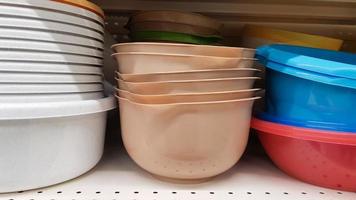 Multi-colored plastic containers of different shapes and sizes with and without lids, stacked in a pile on a store window. Sale of boxes for storage and cleaning. Modern kitchen utensils photo