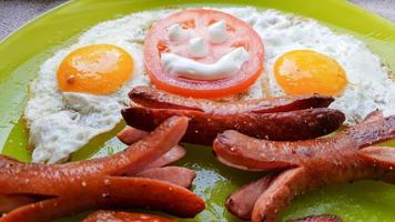 Top view of fried egg and sausages on a green plate, serving breakfast for the baby photo