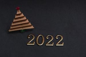New Year's composition. Brown paper christmas tree with golden numbers 2022 on black background with copy space. photo