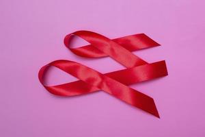 Top view on pink background with red ribbon concept December 1st International AIDS Day close-up. photo