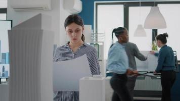 portret van vrouwelijke architect die blauwdrukken op papier bestudeert om een bouwmodel te ontwerpen video