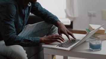 Close up black man hands browsing using laptop computer, searching social media video