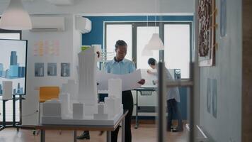 Portrait of woman architect analyzing blueprints plans on paper to design building model video