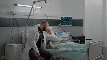 Médico y enfermera revisando al paciente anciano en la cama de la sala de hospital video