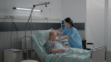 Arzt und Krankenschwester beraten einen kranken Patienten im Bett video