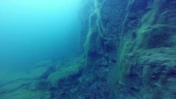 Deep Freediver Exploring a side of a Underwater Cliff into a Quarry