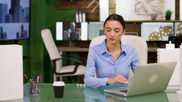 Female chief architect taking a sip of coffee and helping her colleague video