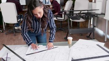 Young female architect drawing line on blueprints video