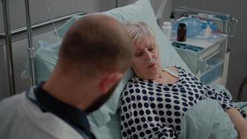 Retired woman with nasal oxygen tube talking to doctor video