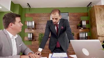 Young businessman in suit leaning over the table in conference room video