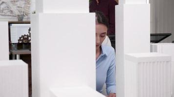 Young female architect looking at 3D printed building models video