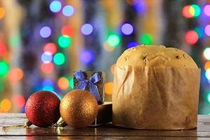 panettone, comida decorativa, sobre mesa de madera, luces borrosas en el fondo foto