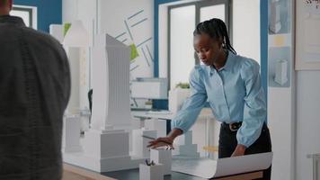 Architect analyzing blueprints plan and building model at work video