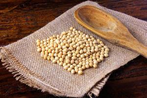 raw and fresh soy beans on rustic fabric on rustic wooden table. Closeup