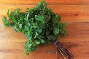 Grupo de menta verde orgánica fresca en la mesa de madera rústica. menta aromática con usos medicinales y culinarios foto