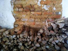 Pila de leña para el invierno para alimentar la chimenea, con fondo de pared rústica.