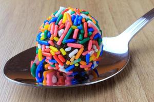 brigadeiro, brigadier, sweet chocolate typical of Brazilian cuisine covered with particles, in a wooden background. photo