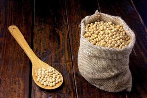 raw and fresh soy beans in rustic fabric bag on wooden table. Closeup photo