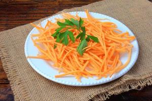 Fresh raw carrot spiralized spaghetti on white plate on rustic wooden table. Concept of healthy food photo