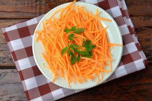 Fresh raw carrot spiralized spaghetti on white plate on rustic wooden table. Concept of healthy food photo