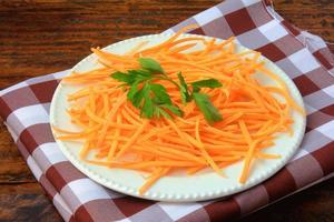 Fresh raw carrot spiralized spaghetti on white plate on rustic wooden table. Concept of healthy food photo
