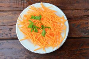 Fresh raw carrot spiralized spaghetti on white plate on rustic wooden table. Concept of healthy food photo