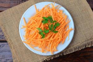 Fresh raw carrot spiralized spaghetti on white plate on rustic wooden table. Concept of healthy food photo