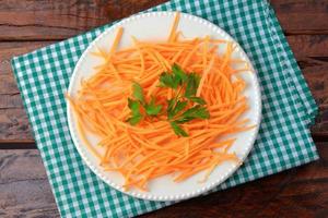 Fresh raw carrot spiralized spaghetti on white plate on rustic wooden table. Concept of healthy food photo