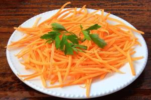 Fresh raw carrot spiralized spaghetti on white plate on rustic wooden table. Concept of healthy food photo