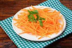 Fresh raw carrot spiralized spaghetti on white plate on rustic wooden table. Concept of healthy food photo