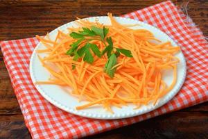 Fresh raw carrot spiralized spaghetti on white plate on rustic wooden table. Concept of healthy food photo