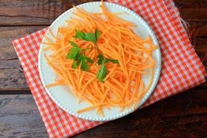 Fresh raw carrot spiralized spaghetti on white plate on rustic wooden table. Concept of healthy food photo