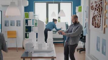 Man using smartphone to design building model and construction layout with maquette in office video