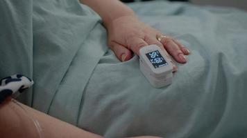Nahaufnahme der Hand eines gealterten Patienten mit Oximeter im Bett video