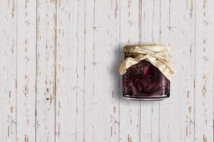 Top up up view Raspberry jam jar isolated on white wooden background. suitable for your design project. photo