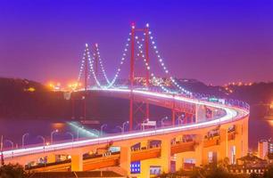 View of The 25th April Bridge - Ponte 25 de Abril with car light trails in haze. Popular landmark of Lisbon, Portugal photo