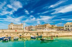 A motorboat sailing along the canal in Ortygia. Cityscape of the famous Sicilian town, Italy photo