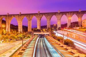 View of the historic aqueduct in the city of Lisbon Aqueduto das Aguas Livres, Portugal. Train station Campolide at the evening photo