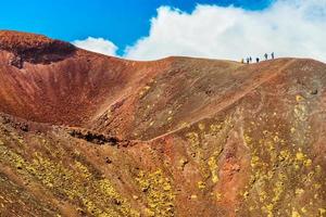 A group of people standing on the edge of the volcano crater, Mount Etna, Sicily, Italy photo