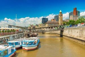 Cityscape of Hamburg, Germany. View of the city with tourist ships, river terminal, passenger boarding bridge over the canal and the blue sky photo