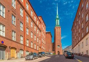 Vista de una calle de Helsinki con la tradicional arquitectura de ladrillo rojo y una iglesia kristuskyrkan, en el estilo neogótico finlandés, Finlandia foto