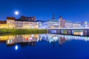 ciudad de noche reflejada en el agua. panorama nocturno de una antigua ciudad europea. paisaje urbano de malmo, suecia foto