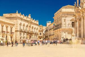 View of The Central Square in Ortygia, Ortigia, Piazza Duomo with walking people. Historical buildings in the famous Sicilian town Syracuse, Siracusa, Italy photo