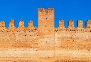 Old brick wall of medieval Italian fortress against the blue sky photo